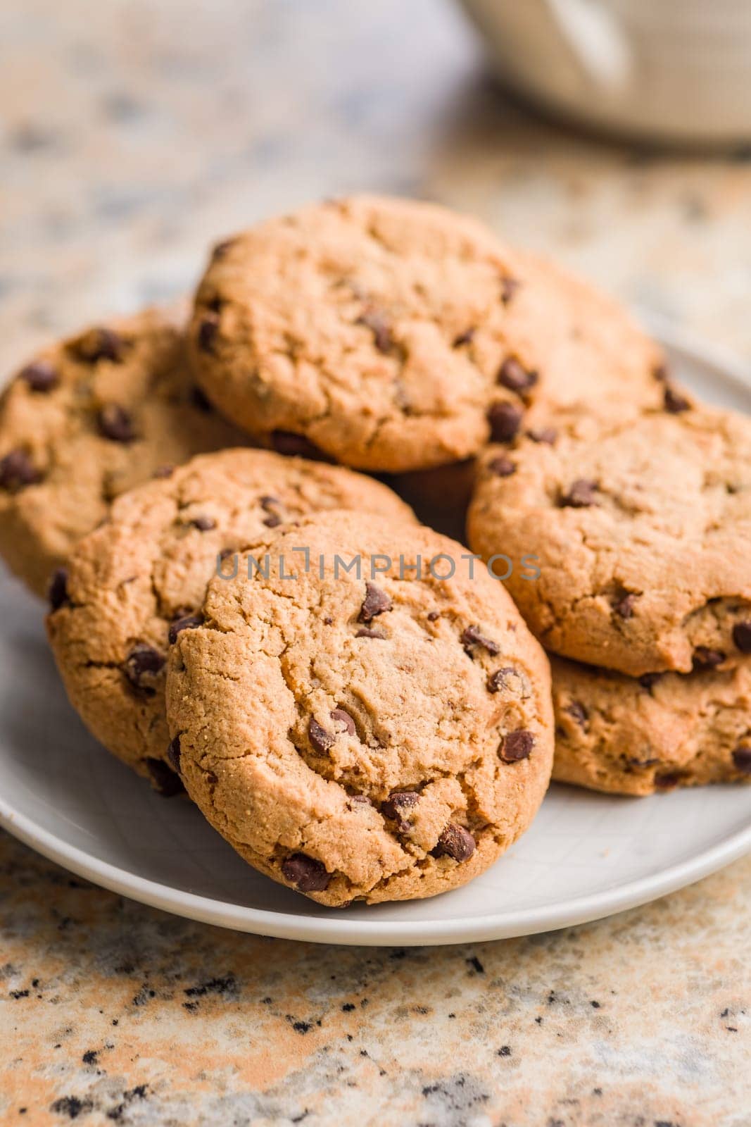 Chocolate chip cookies on plate on a kitchen table.