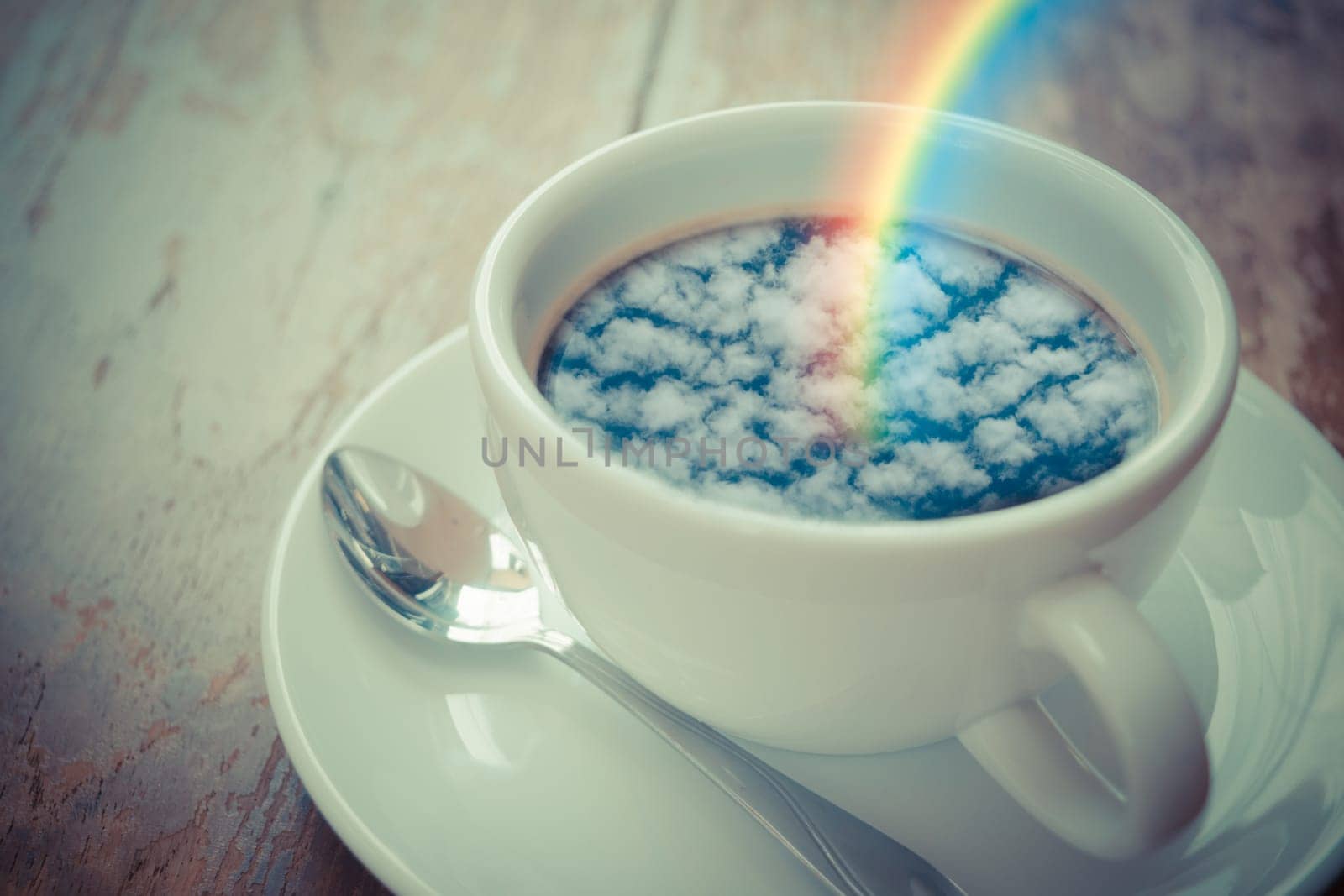 Blue sky cloud with rainbow reflection on Coffee in white cup on wood table , process in vintage style