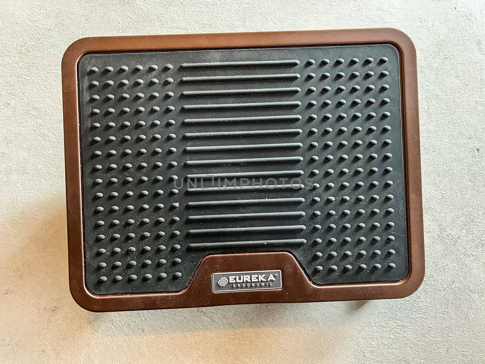 Castle Rock, Colorado, USA-April 25, 2023-A close-up view of an adjustable metal foot rest with a brown finish and a rubberized grip The design features a locking mechanism for stability and foldable legs for easy storage Ideal for ergonomic support and comfort in home or office settings