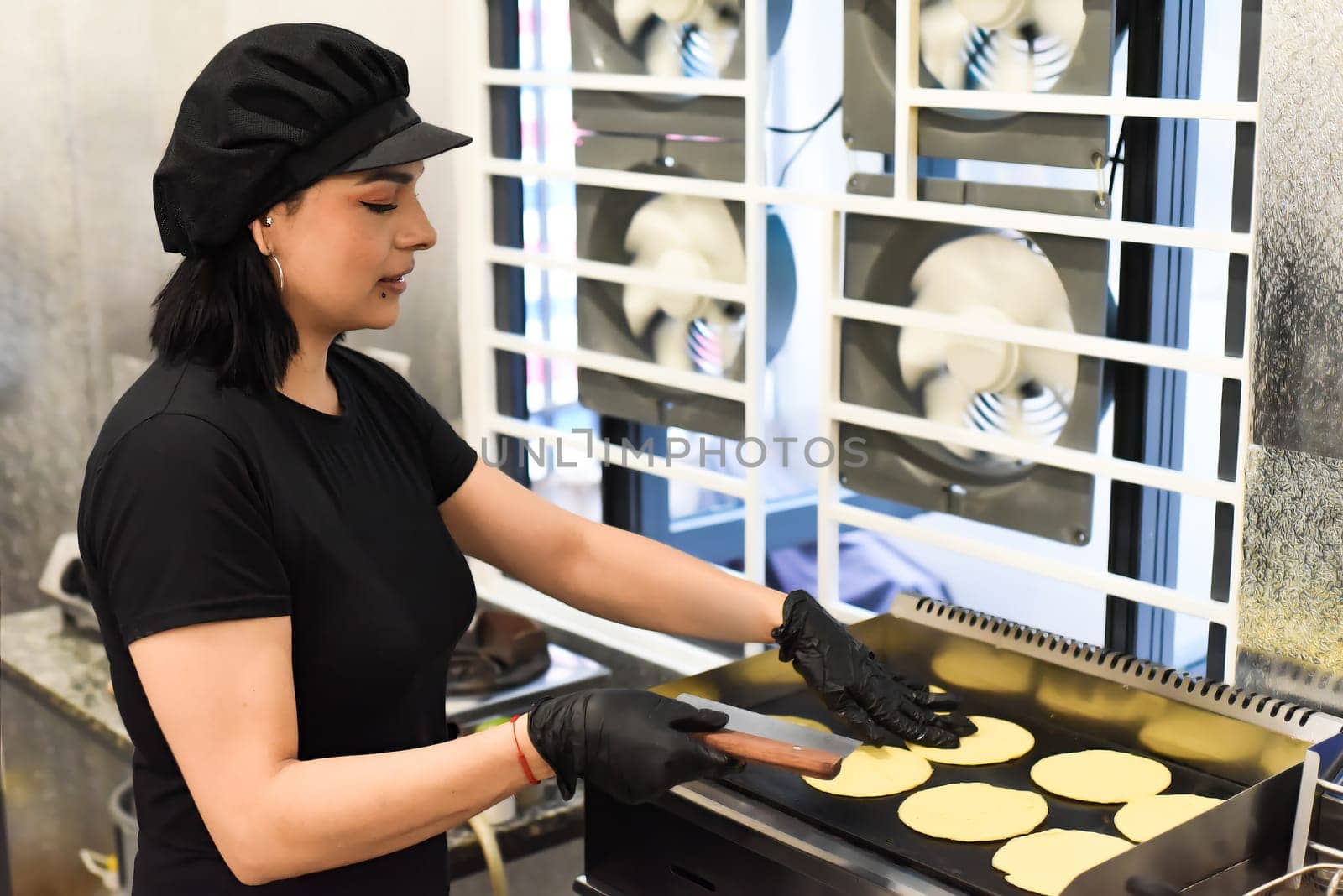 Mexican woman making tacos in a kitchen of a mexican cafe