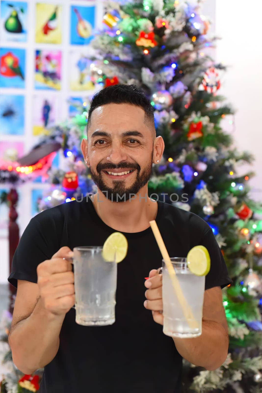 Mexican man holding mexican drinks Horchata water and lemon juice against christmas tree