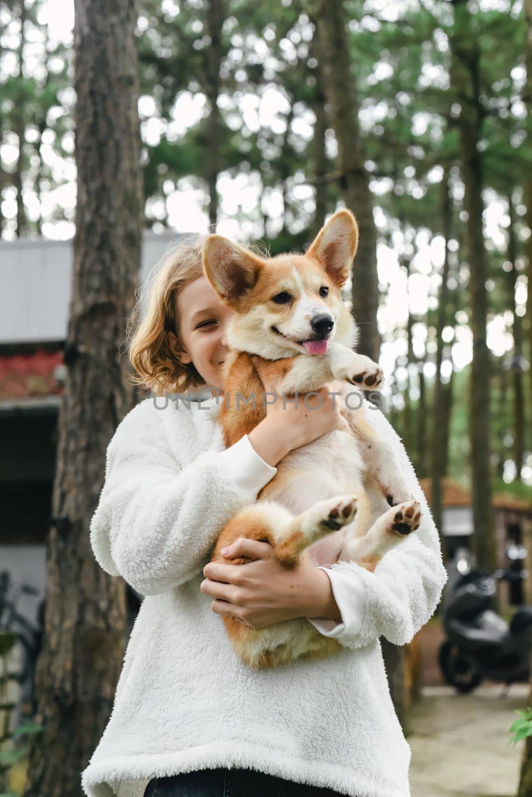 Little cute girl holding her corgi dog on an autumn day