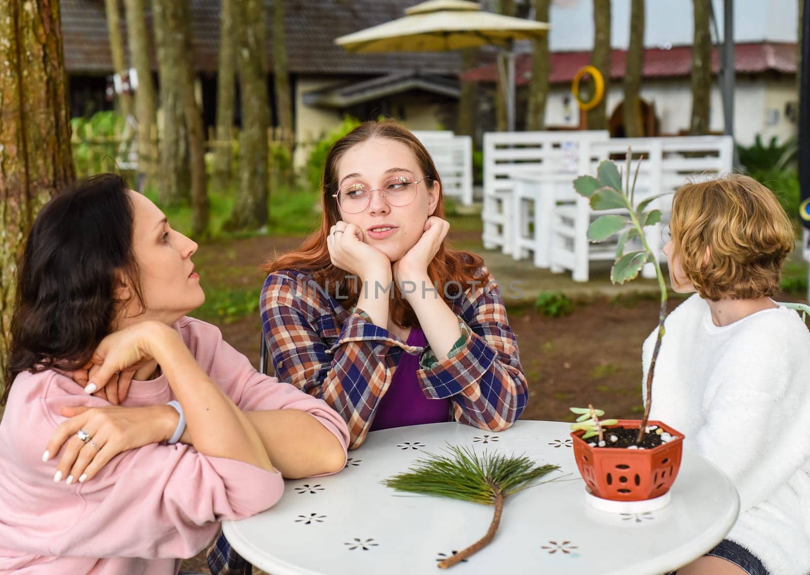 Mother and her two daughters sitting by the table and talking together