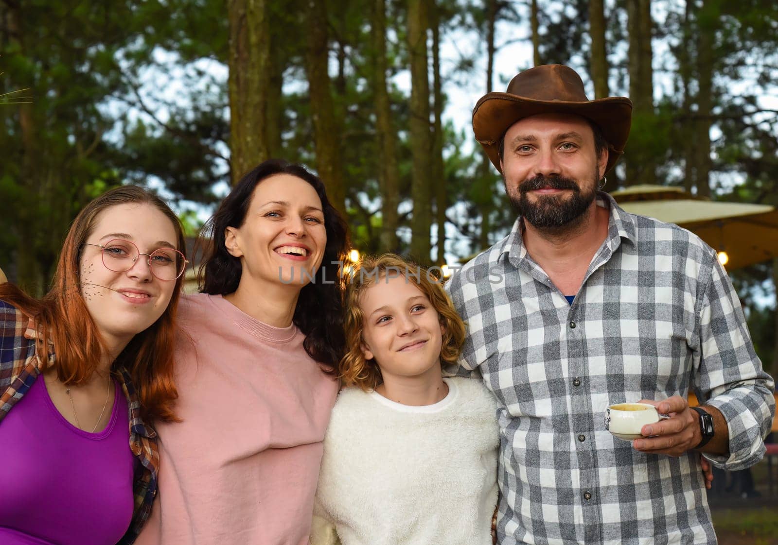 Family members father, mother and two daughters laughing in camping in the forest
