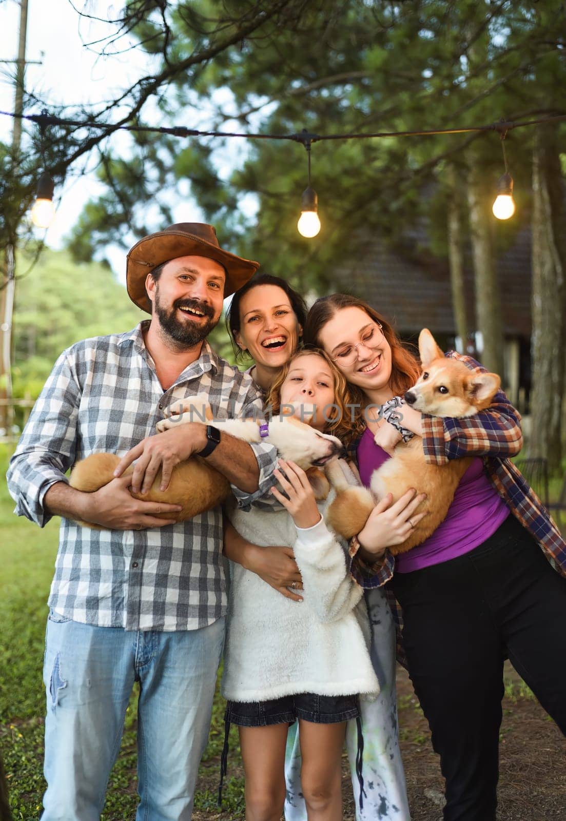 Family members father, mother and two daughters with corgi dogs in the forest