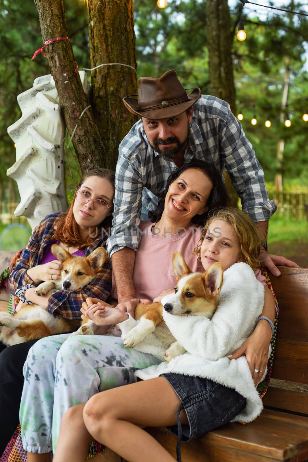 Family members father, mother and two daughters with corgi dogs in the forest