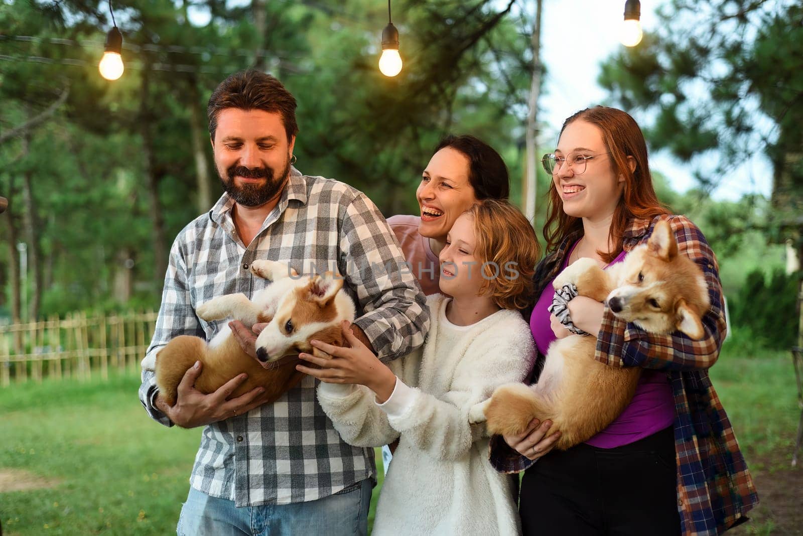 Family members father, mother and two daughters with corgi dogs in the forest