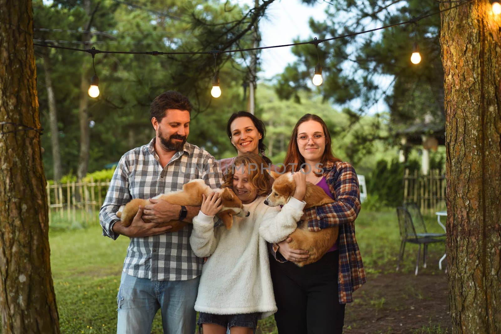 Family members father, mother and two daughters with corgi dogs in the forest