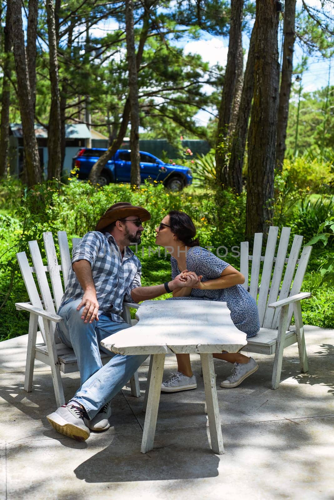 Young married couple kissing and sitting in the forest on a sunny day