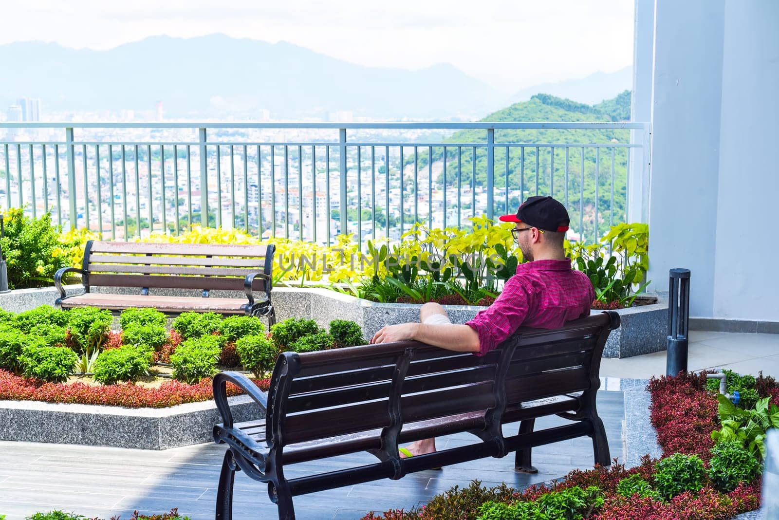 Young tourist man resting on the bench and looking at Nha Trang city