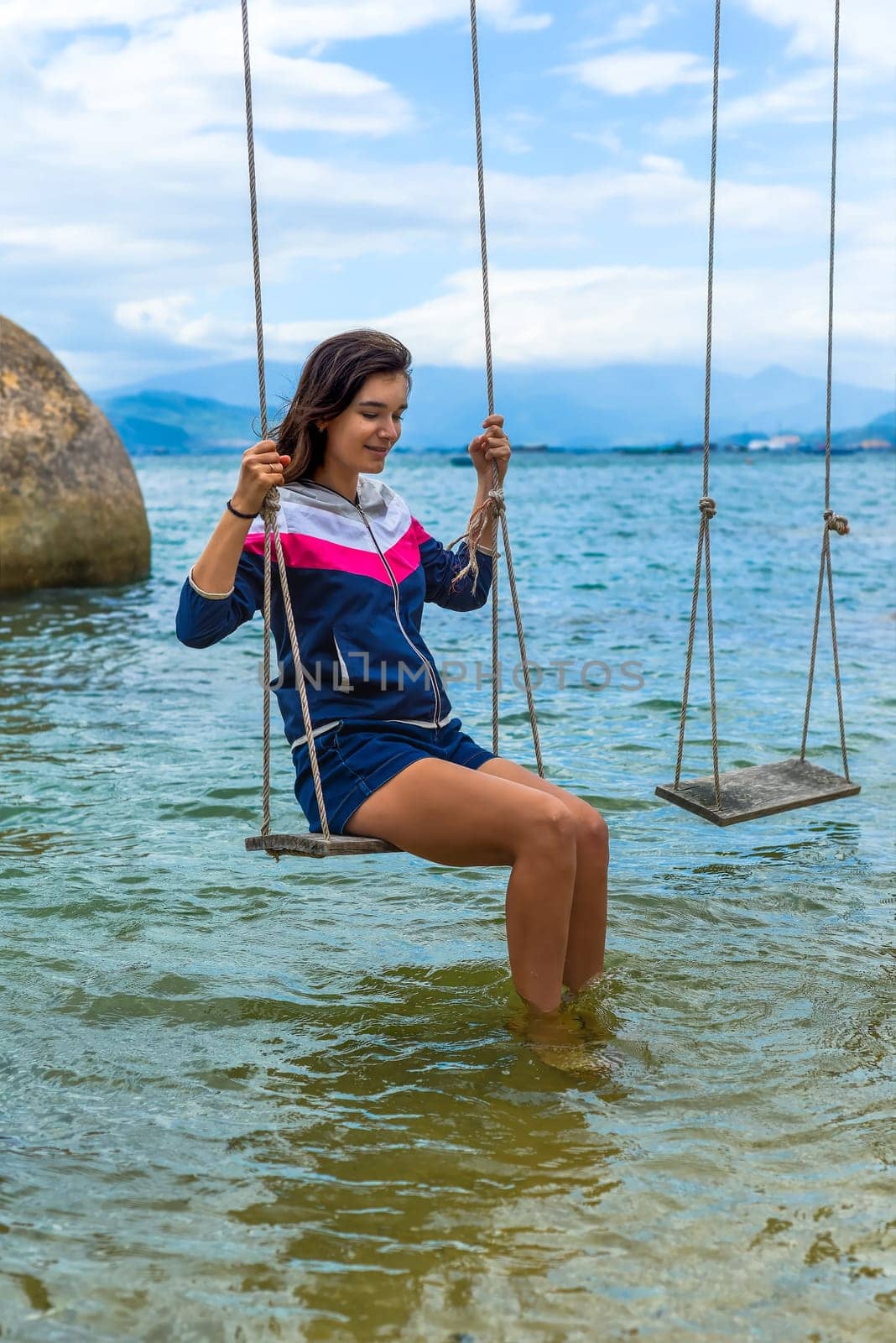 Young brunette woman riding a swing in the sea in vietnam