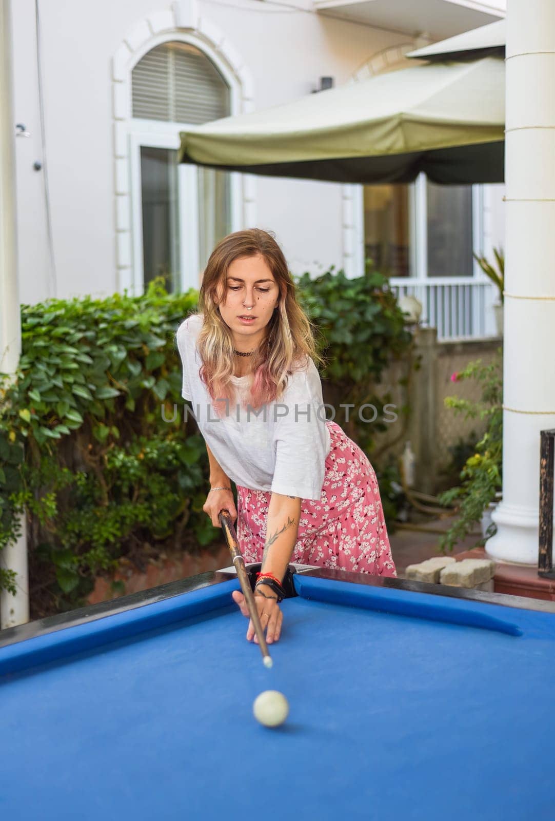 Young blond woman playing billiards in the backyard