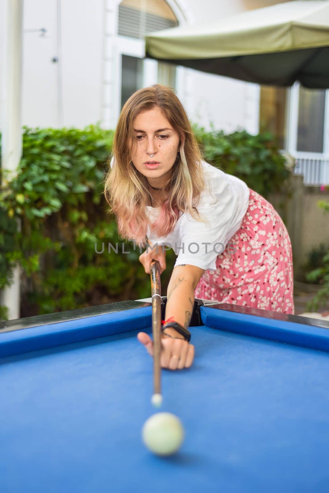 Young blond woman playing billiards in the backyard