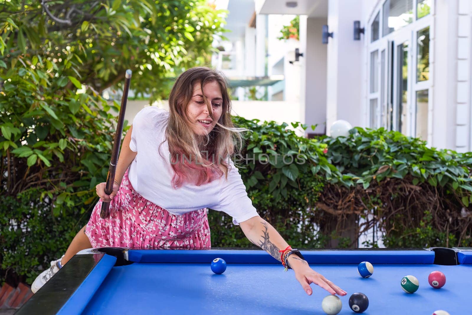 Young blond woman playing billiards in the backyard