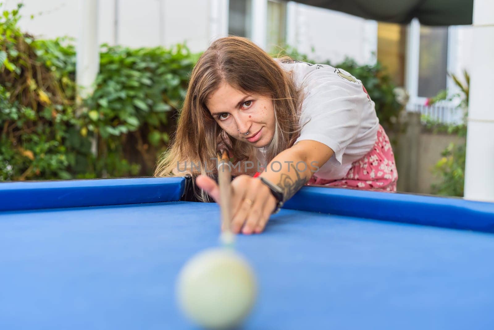Young blond woman playing billiards in the backyard