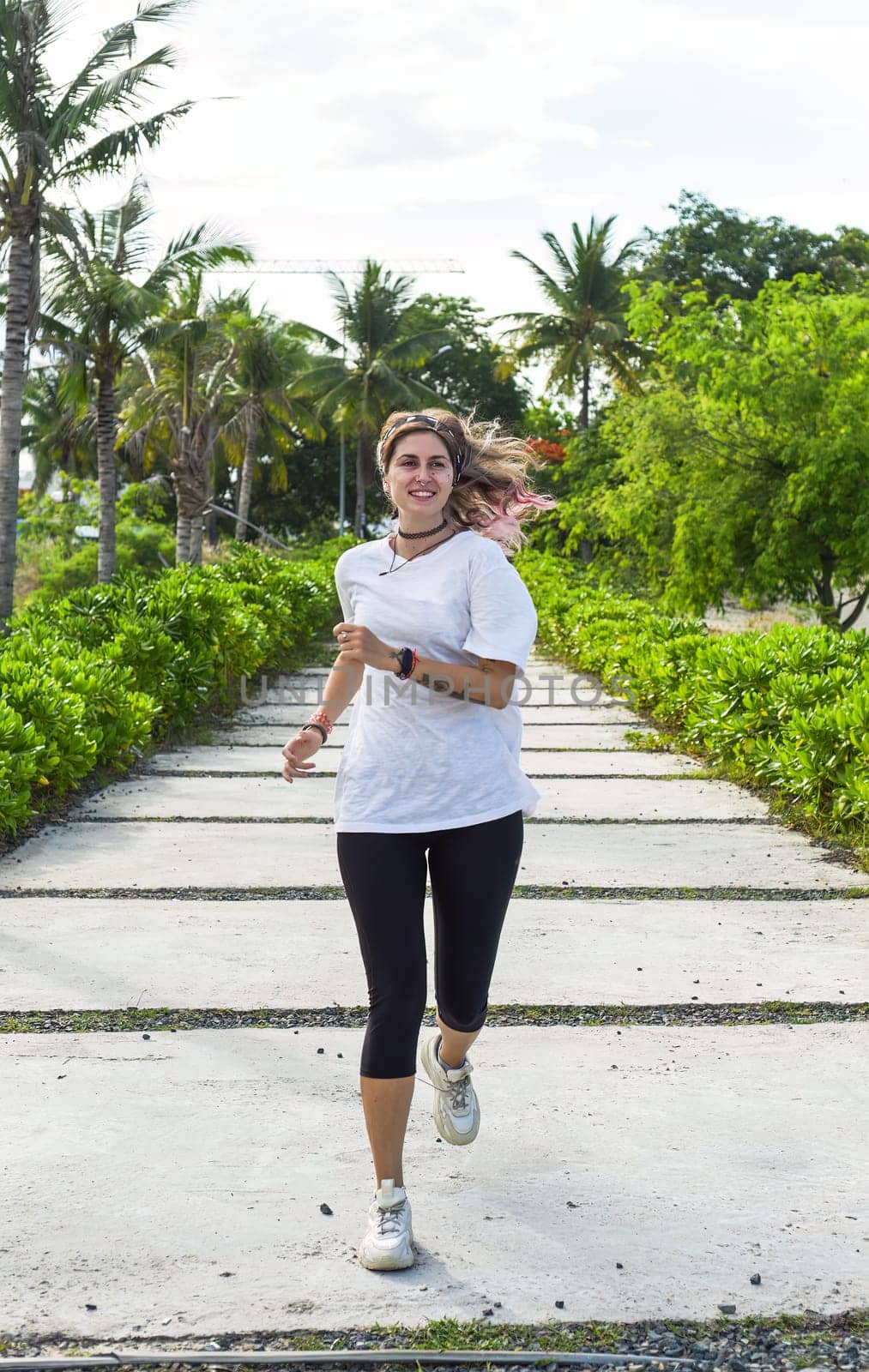 Beautiful woman in sport clothes running into a camera