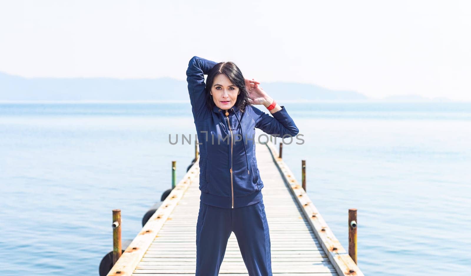 45 y.o. Russian woman stretching  on a wooden pier by the Japanese sea