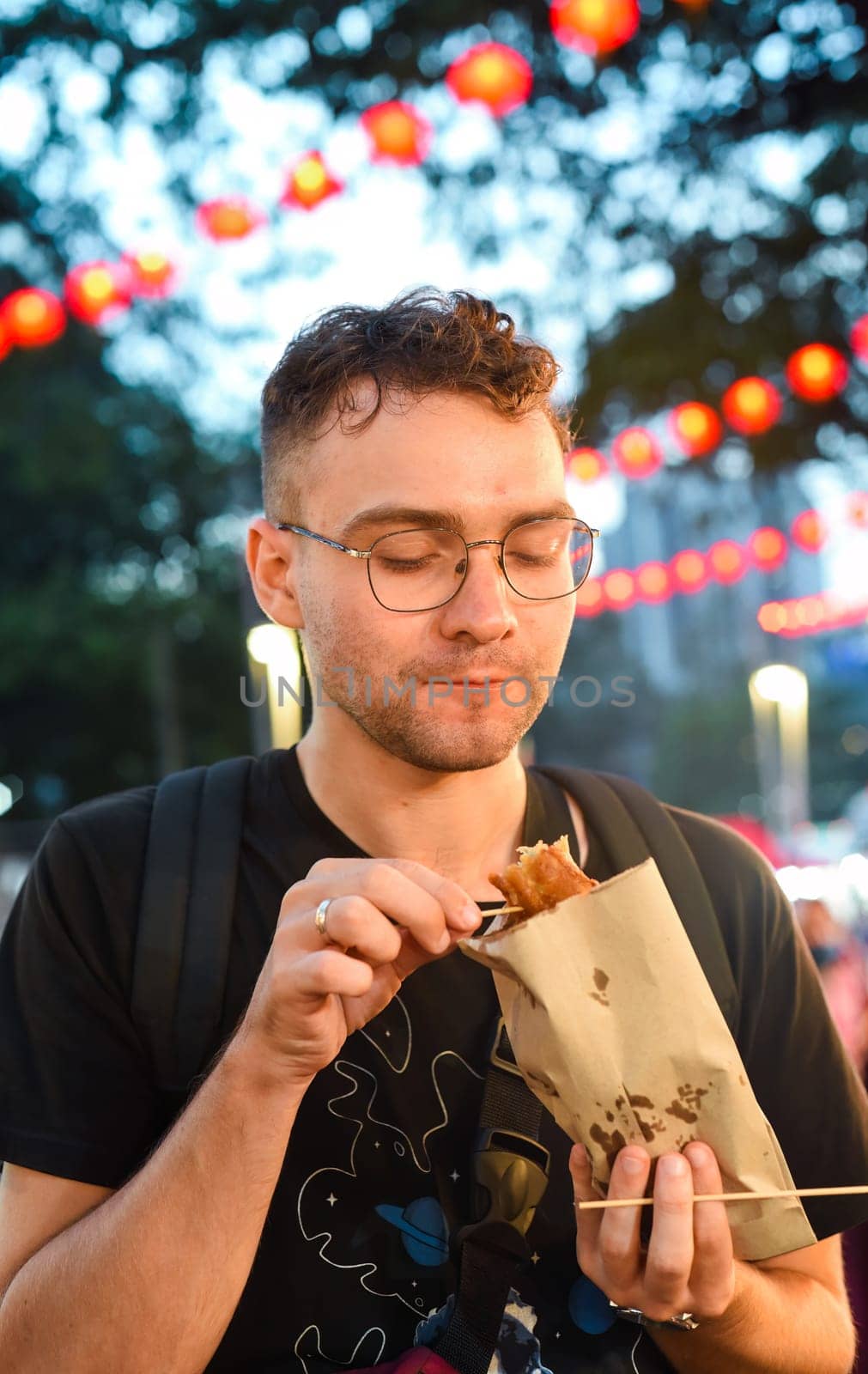 Young man tourist eating fried banana in Jalan Alor street food in Kuala Lumpur, Malaysia