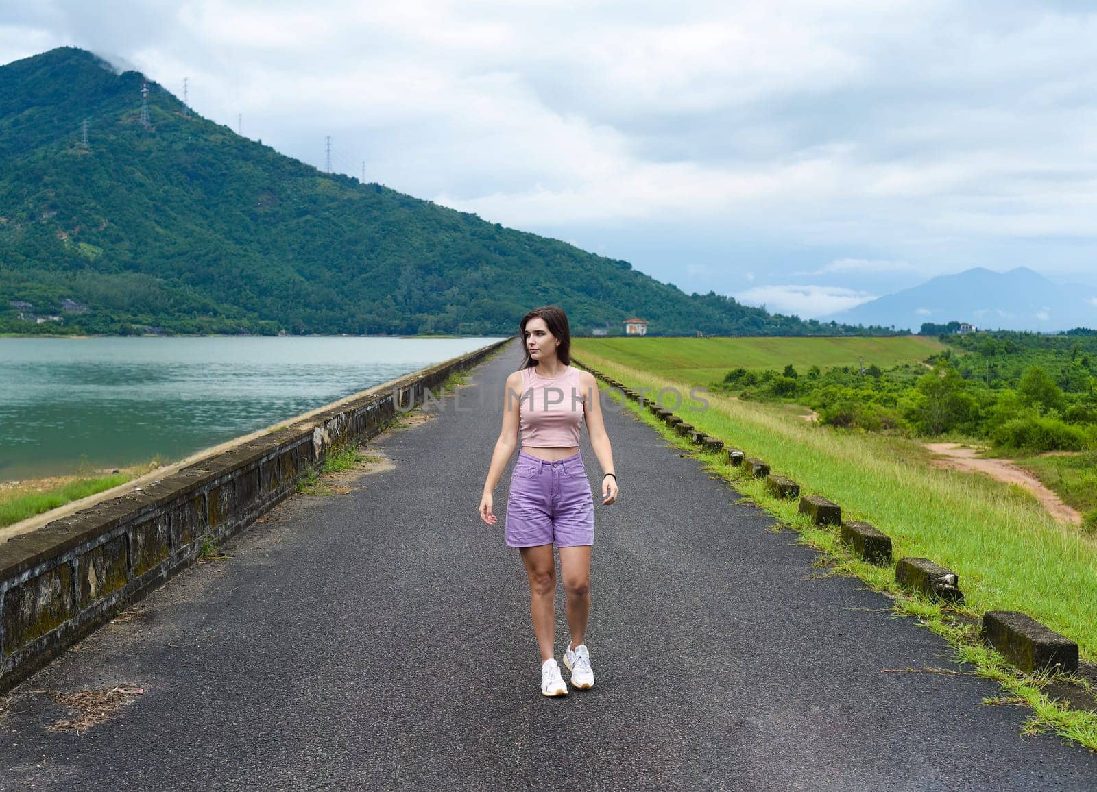 Young russian woman traveler with depressed and sad face walking alone near lake and mountains in Khanh Hoa Province, Vietnam