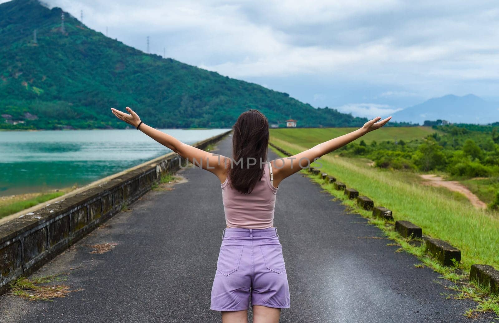 Young russian woman traveler with opened arms near lake and mountains in Khanh Hoa Province, Vietnam