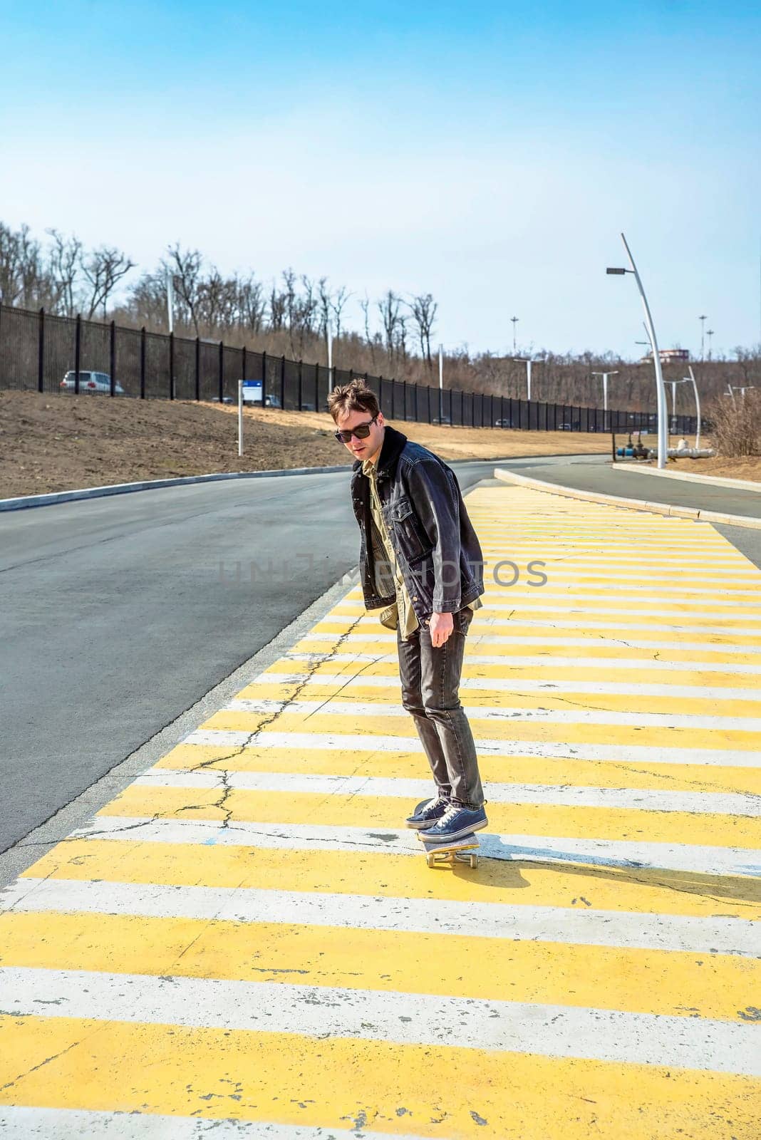 Young man riding a skateboard on a pedestrian cross road