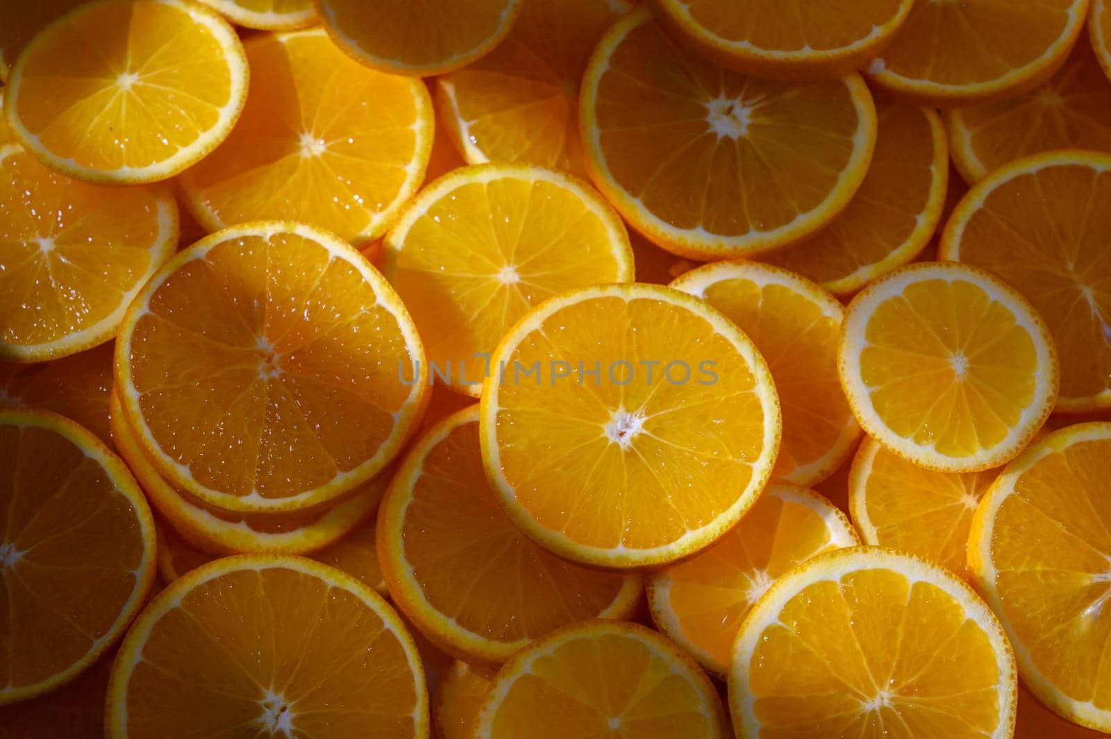 A colorful arrangement of orange slices reveals their juicy texture under warm sunlight, showcasing natural beauty.