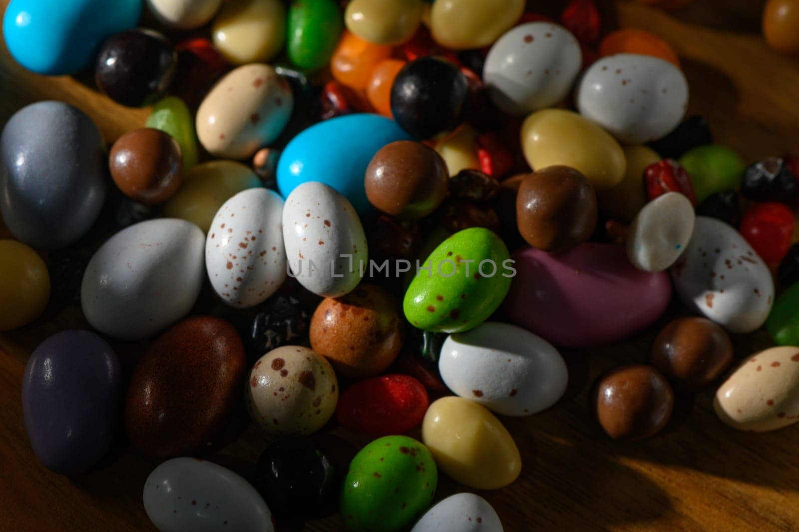 A lively mix of candies in various shapes and colors scattered across a wooden surface, inviting sweetness and joy.