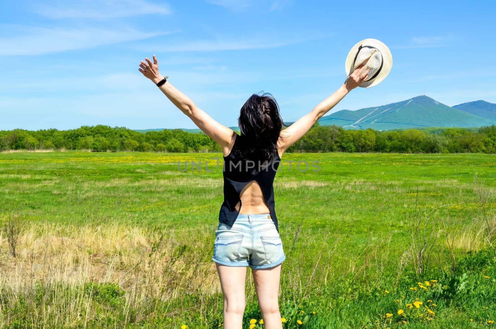 Brunette woman with hat embracing nature with open arms in countryside. copy space
