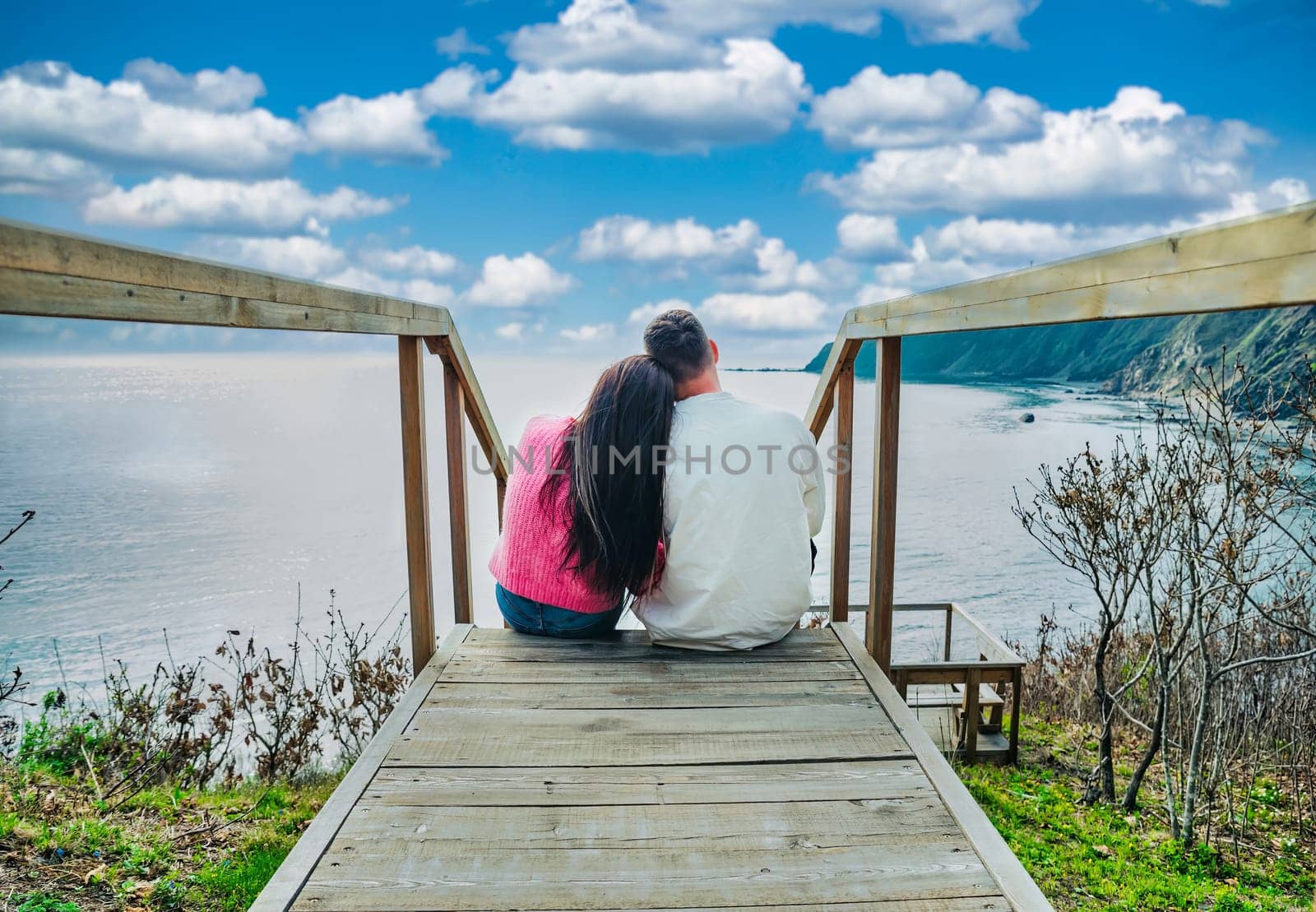 married couple sitting together on the stairs and looking at blue sky