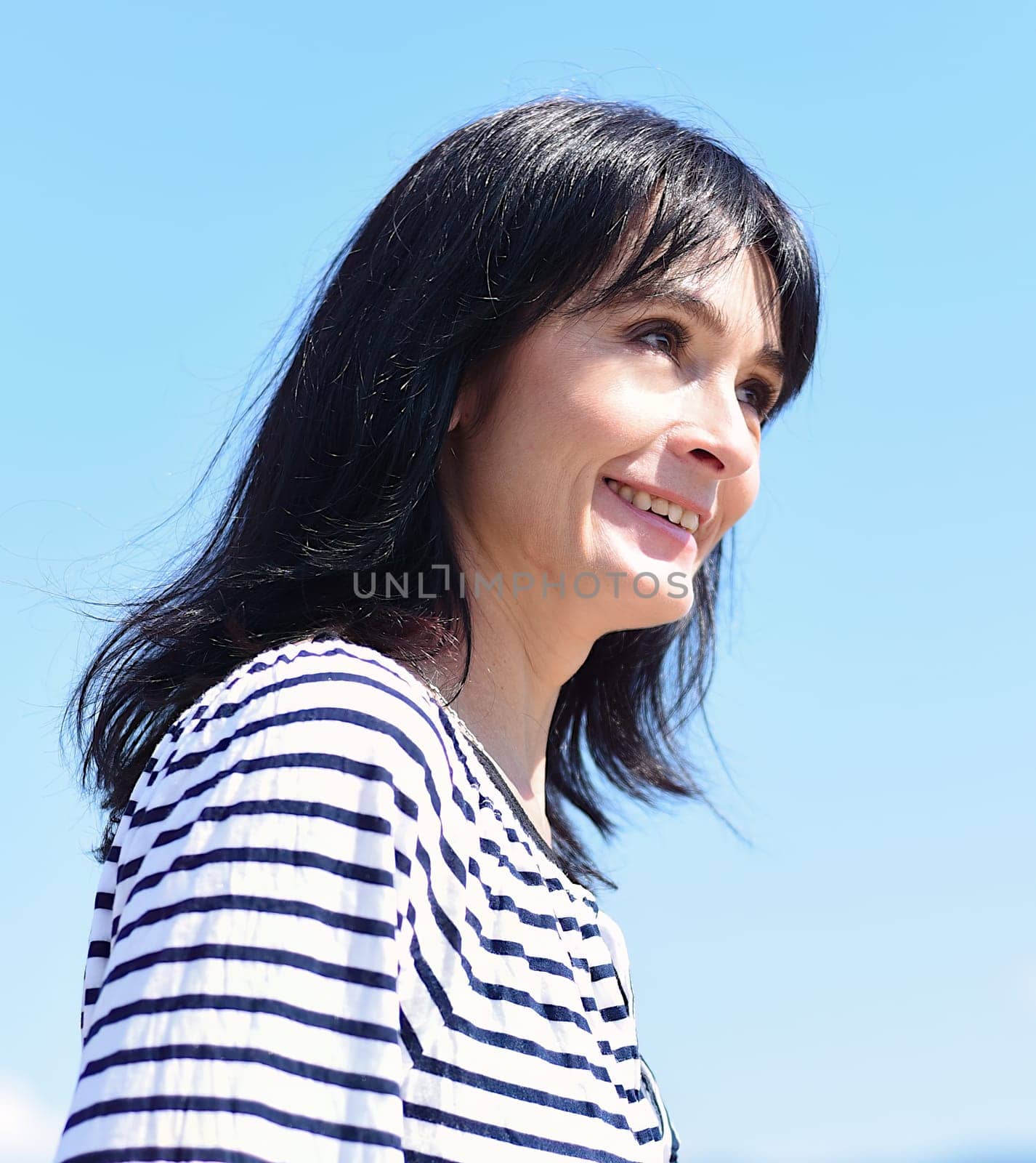 45 years old Russian woman laughing and standing against blue sky