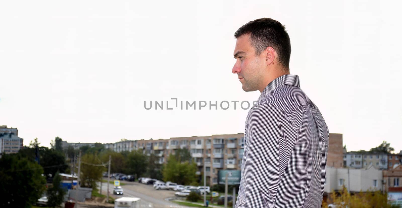Man in office clothes standing on the balcony and looking at the old dirty Russian city Bolshoy Kamen.  depressive concept of loneliness, failure, loss of money