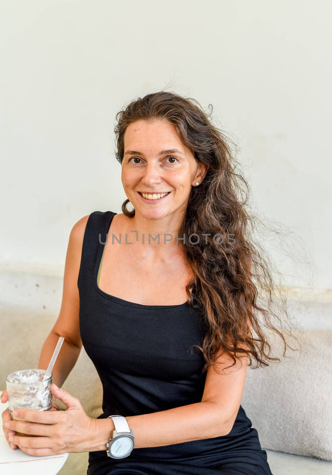 Successful 40 year old sitting in a cafe with glass of ice coffee and looking left