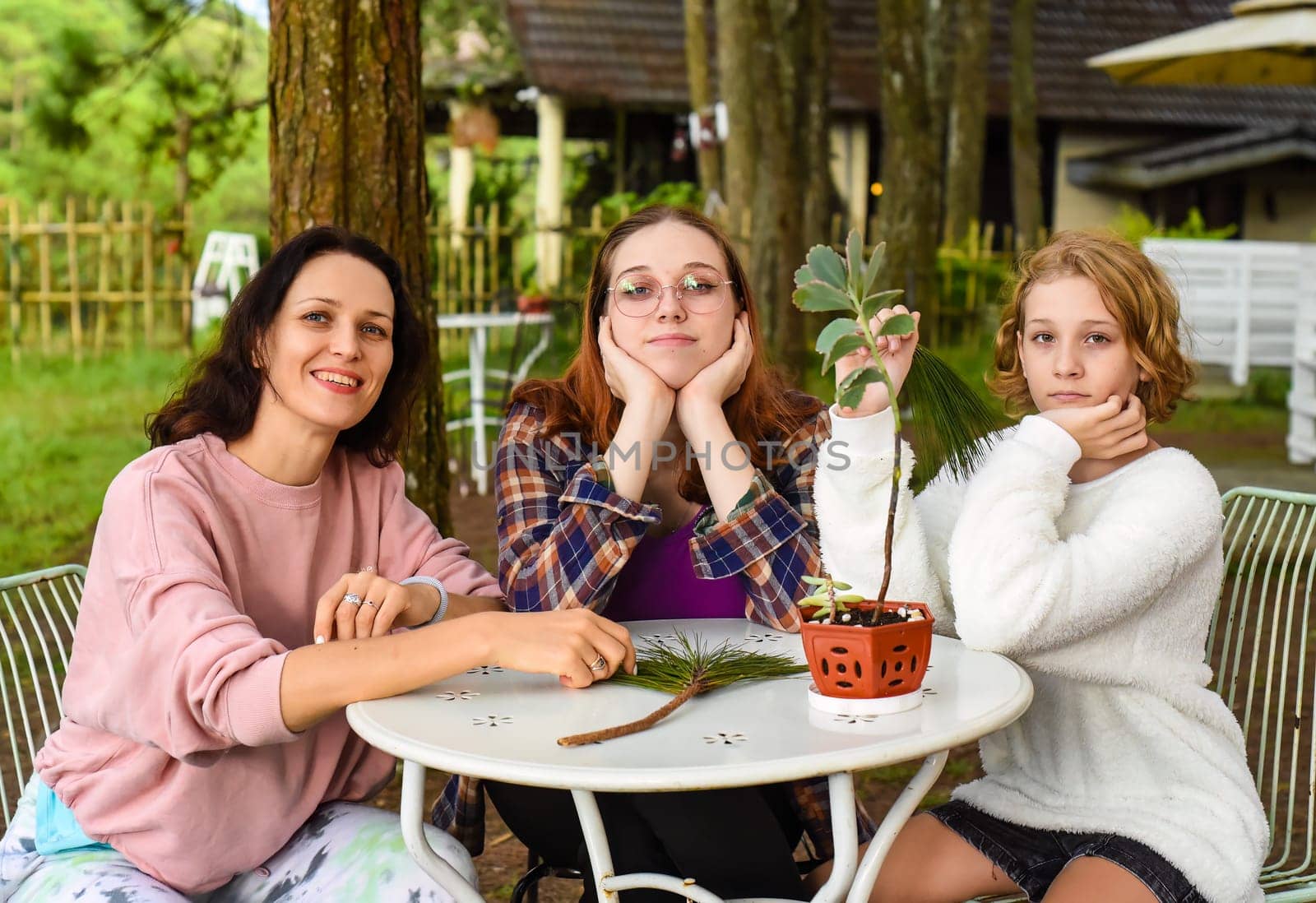 Mother and her two daughters sitting by the table and talking together