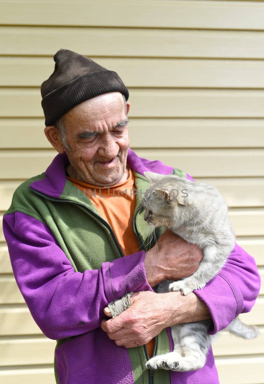 Old Russian man holding a cat and laughing