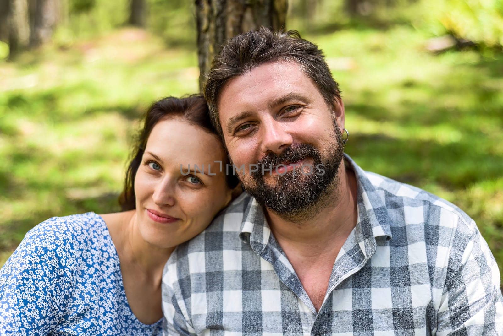 Portrait of young married couple sitting in the forest on a sunny day