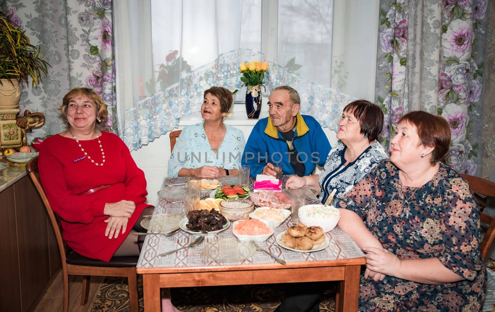 Family and senior friends eating together and watching tv show together at home