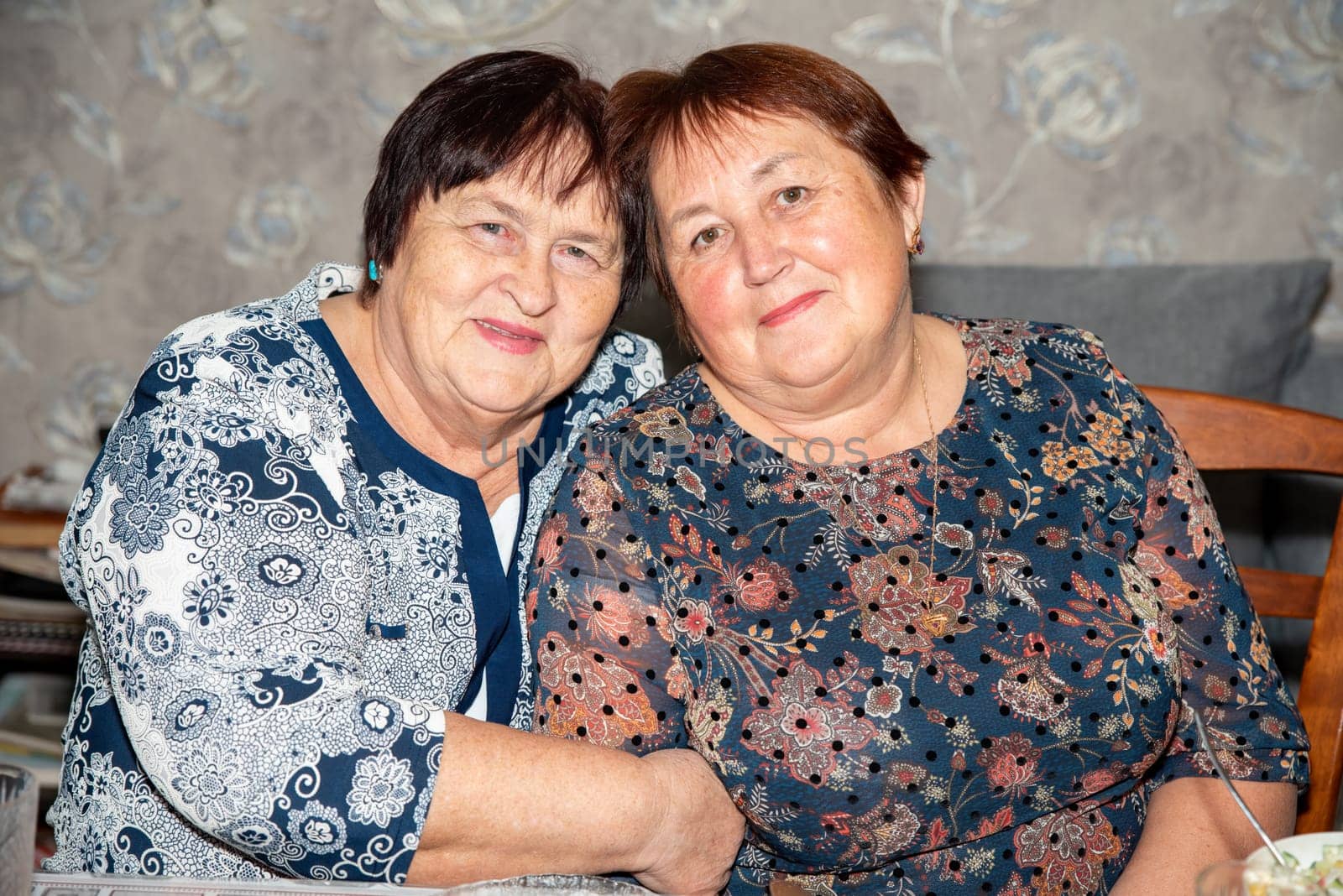 Two cheerful women, aged 70 and 60, share a warm moment together. Capturing friendship, happiness and beauty of aging gracefully. Perfect for themes of senior companionship and life celebrations
