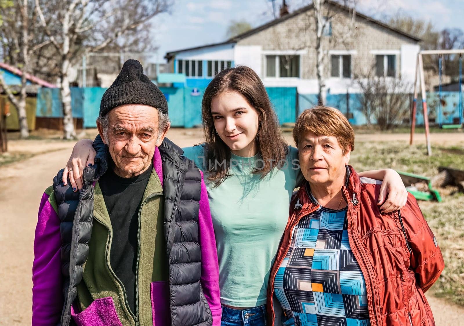 Portrait of 75 years old grandparents and their granddaughter in russian village together