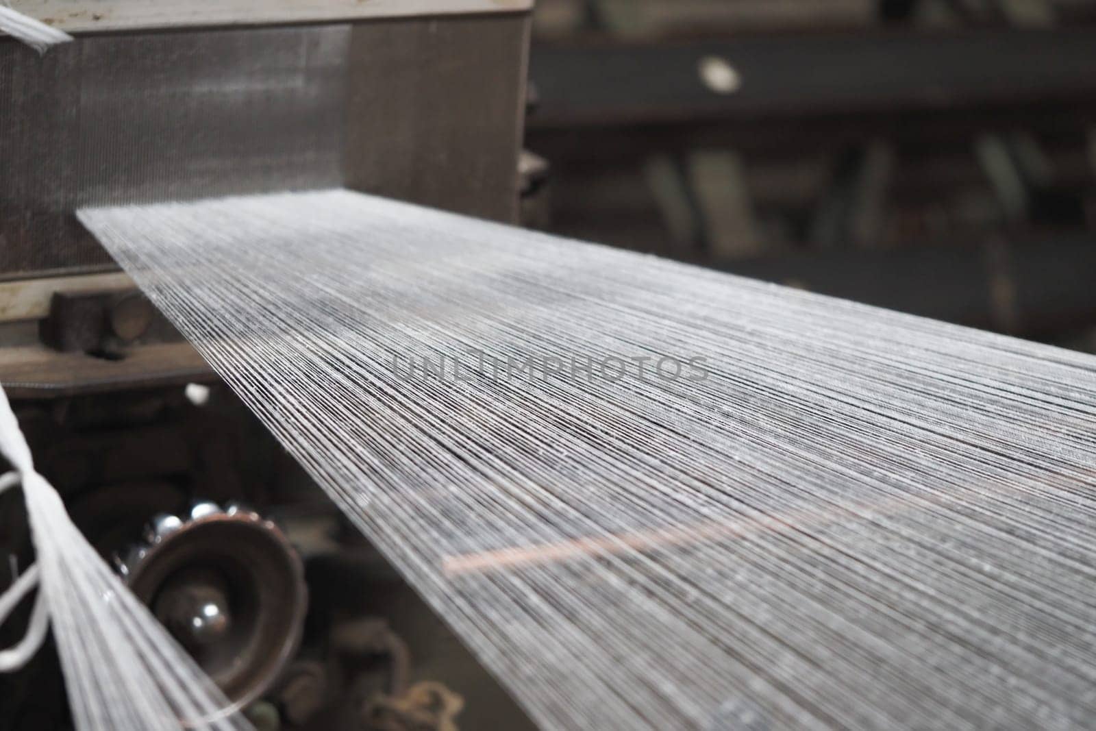 Threads are being woven together in a textile factory during production.