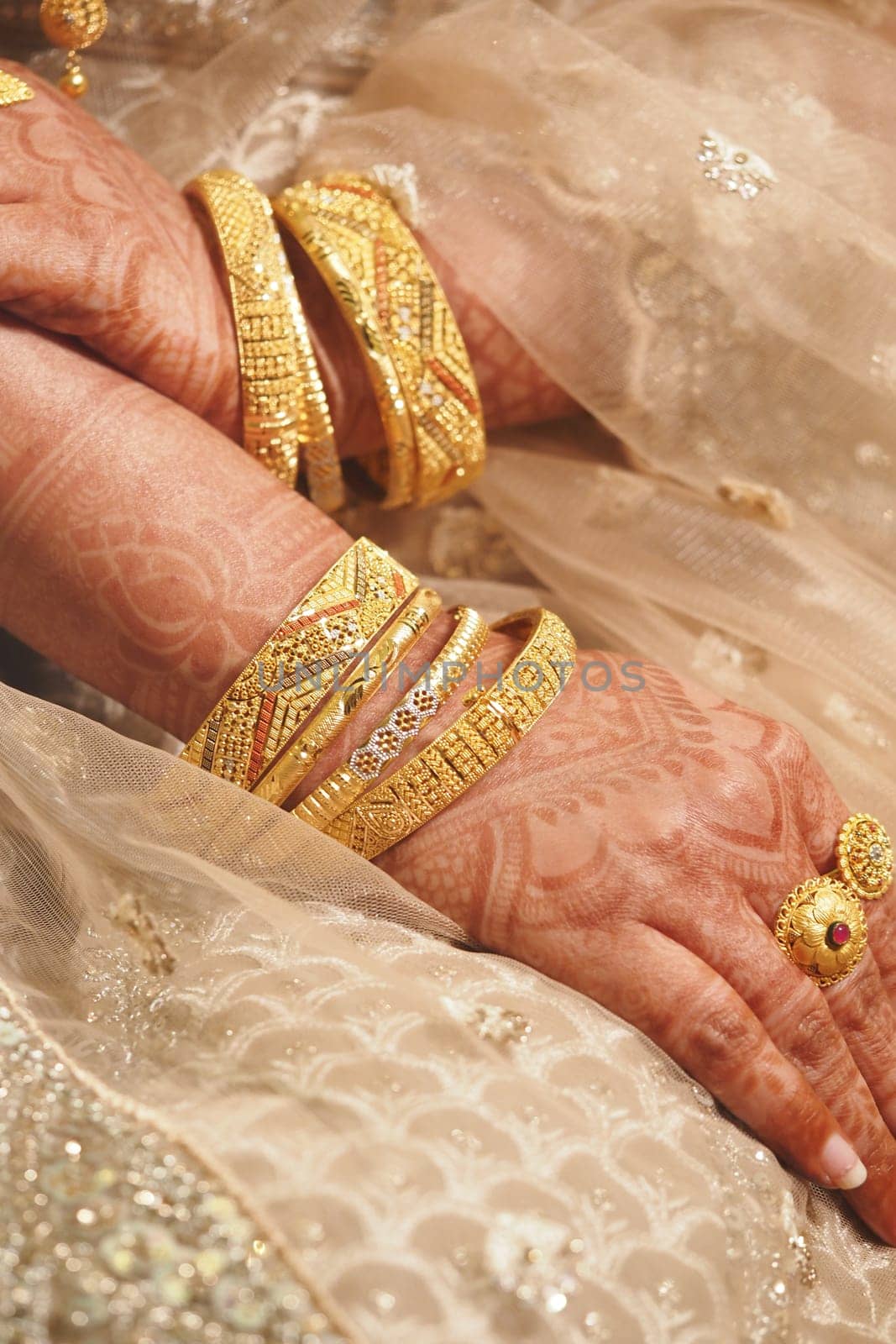 Hands showcasing intricate henna designs and multiple golden bangles.