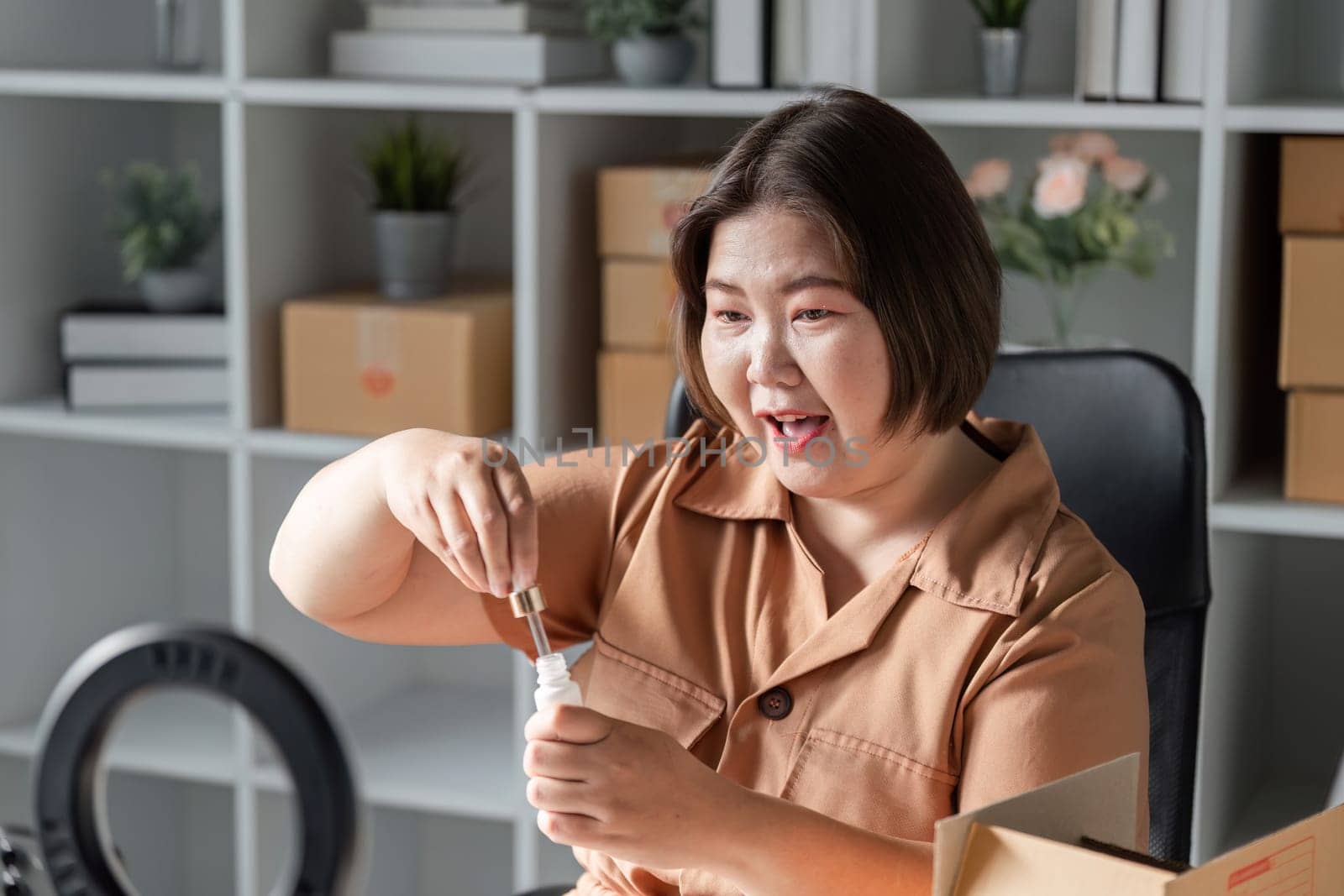 A beauty content creator enthusiastically demonstrates a skincare serum, connecting with her audience in her stylish office space, while showcasing the product's benefits.