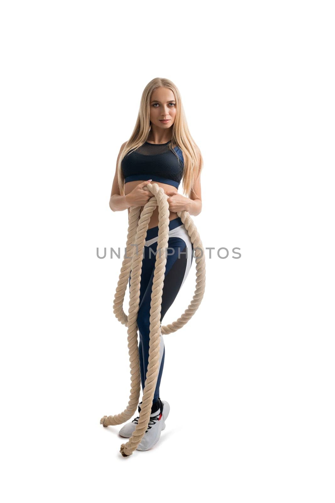 Beautiful blonde fitness model exercising with a rope isolated full-length shot