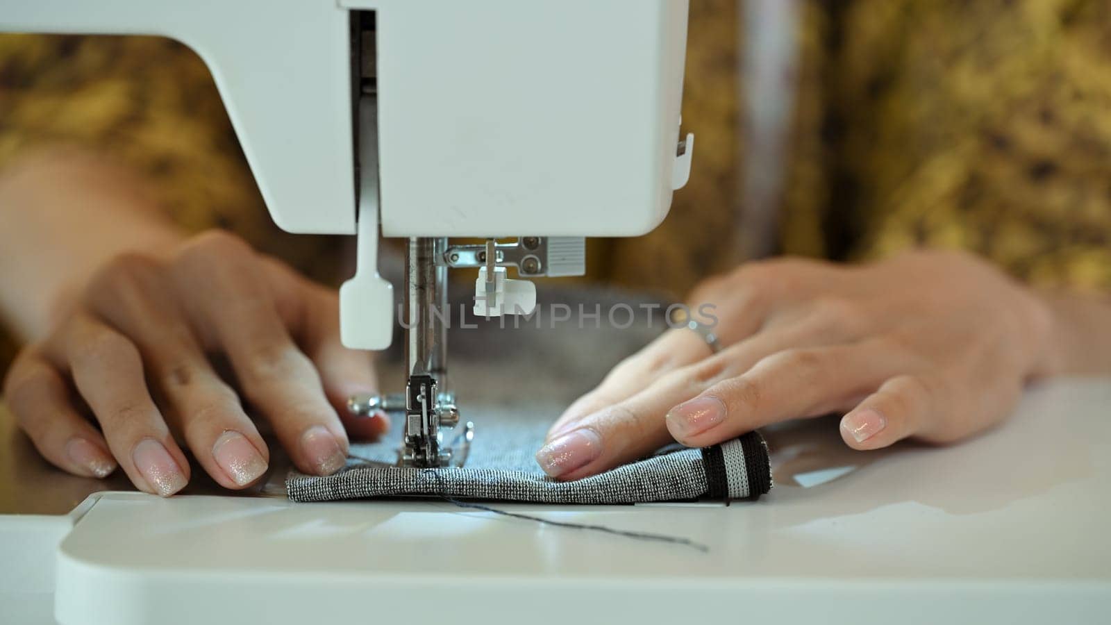 Close up of professional seamstress working on a sewing machine. Creative entrepreneurship concept.