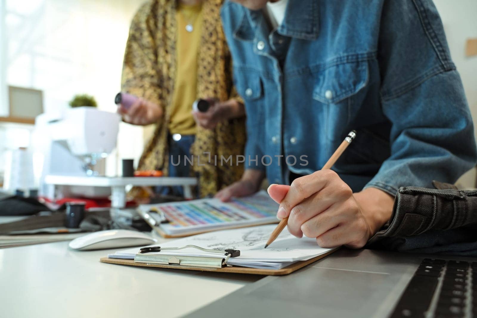 Close up of fashion designer sketching a new clothing design on a clipboard.
