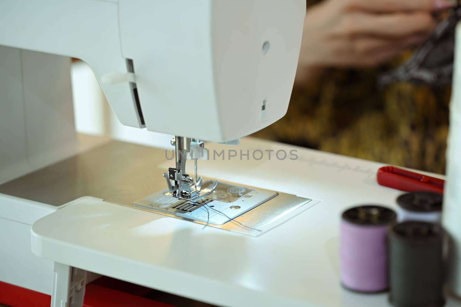 Close up of a sewing machine with thread and fabric at fashion designer workspace.