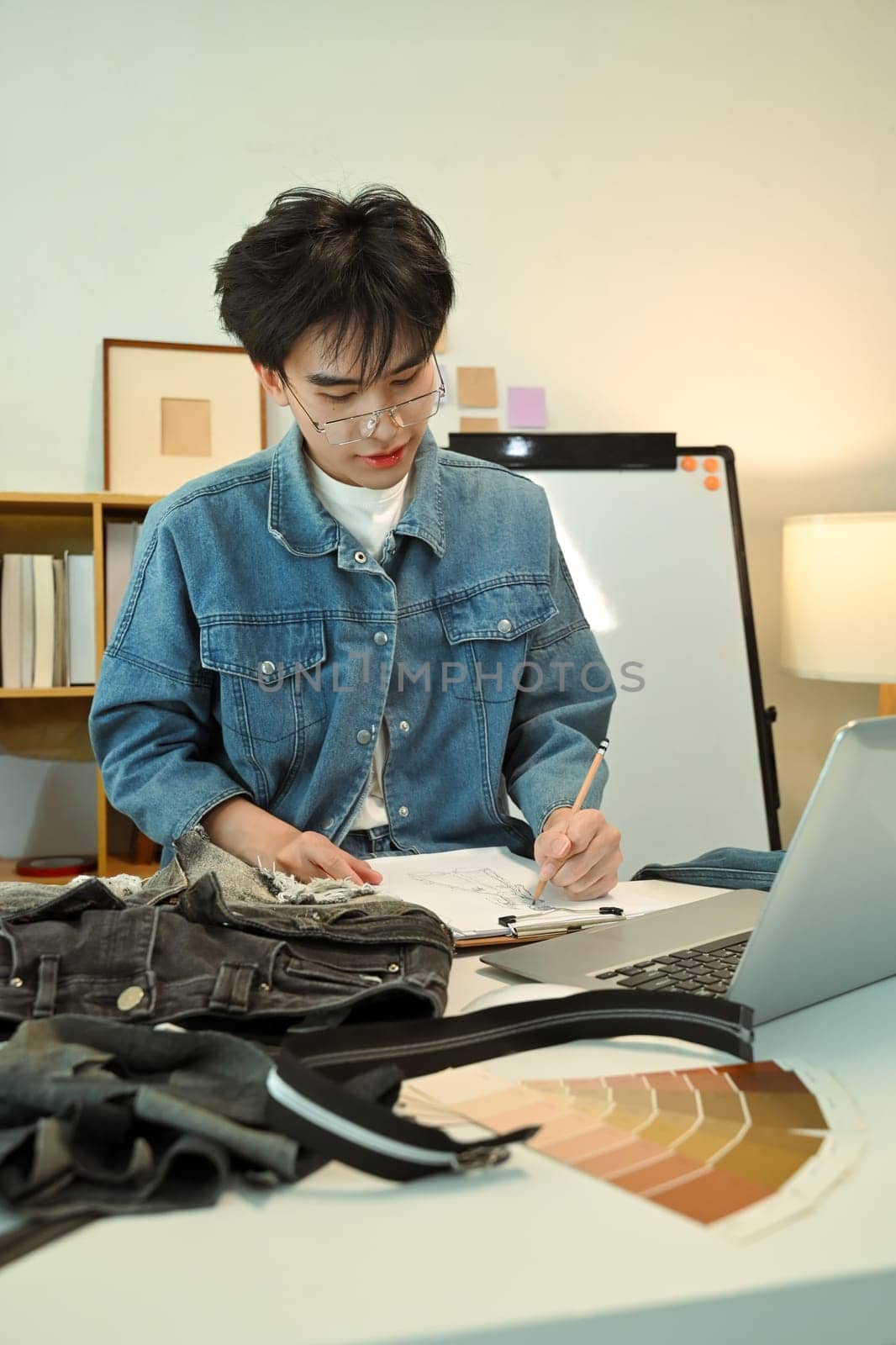 Creative young fashion designer sketching a clothing design at his workspace.