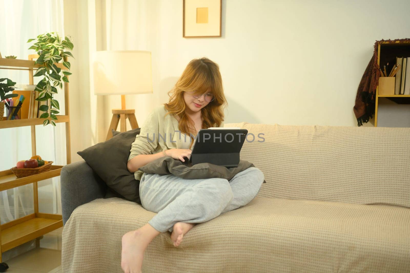Relaxed young woman using digital tablet for online learning or remote work at home.