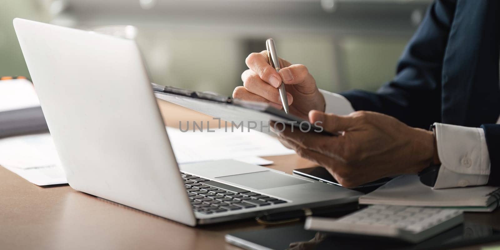 An elderly businessman utilizes digital tools in a professional office setting showcasing productivity and modern work dynamics.