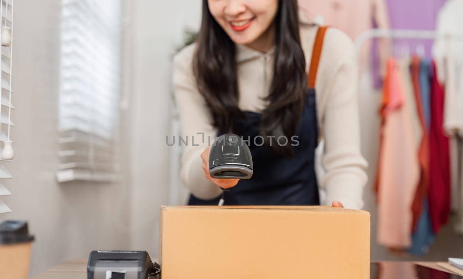 A diverse young woman using a barcode scanner to scan a cardboard box in a retail environment, preparing for inventory management.