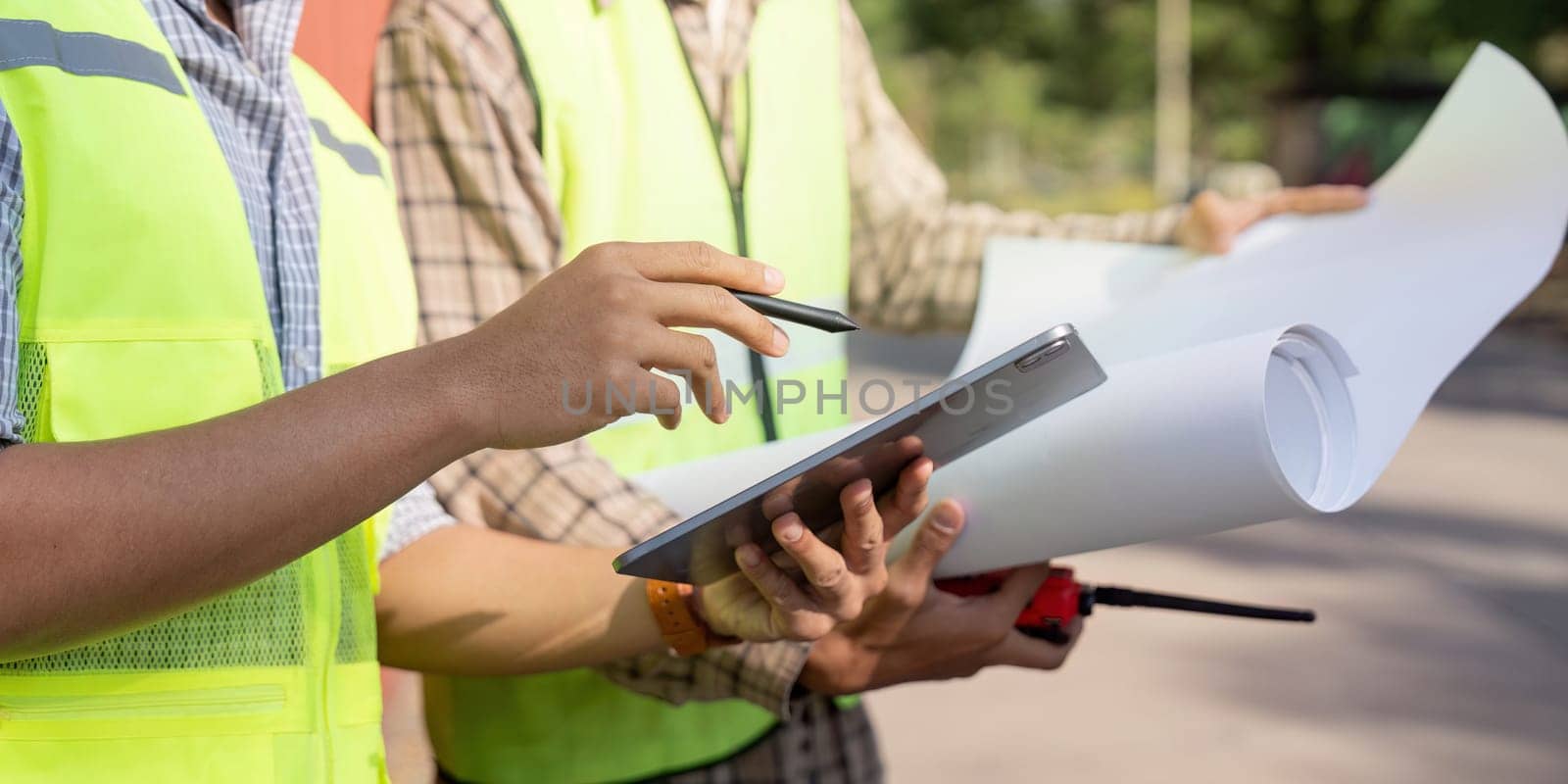 Two logistics engineers collaborate on site plans ensuring efficient operations and resource management in construction.